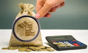 Dłoń z lupą bada worek z monetami i kalkulator. Pytanie: ile wynosi podatek od darowizny 100 tys.?