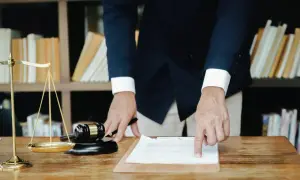 Prawnik wyjaśnia, jak wyliczyć podatek od spadku. Przykład na dokumencie, obok wagi sprawiedliwości i młotka.