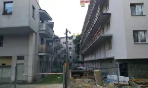 Nowe bloki mieszkalne, typowa patodeweloperka, z balkonami i placem budowy w tle.
