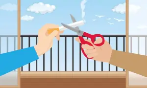 Dwie ręce przecinają nożyczkami papierosa na balkonie. Czy można palić na balkonie? Ta ilustracja sugeruje, że nie.