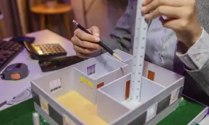 Architekt mierzy model domu, planując każdy metr sześcienny.