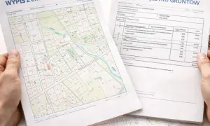 Ręce trzymają wypis i wyrys z rejestru gruntów. Obok leży kalkulator. Dokumenty zawierają mapę działek i tabelę z danymi.