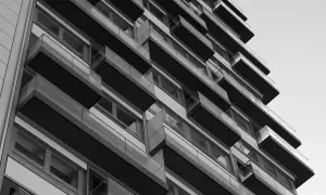 Nowoczesny budynek z balkonami, tworzący geometryczną kompozycję. Widok z dołu, podkreślający architekturę. WM rejestracja.