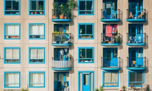 Elegancka loggia i balkon z niebieskimi ramami okiennymi, pełne zieleni i suszącego się prania, tworzą kolorowy obraz miejskiego życia.