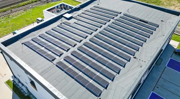 Duży płaski dach pokryty panelami fotowoltaicznymi, które zbierają energię słoneczną.