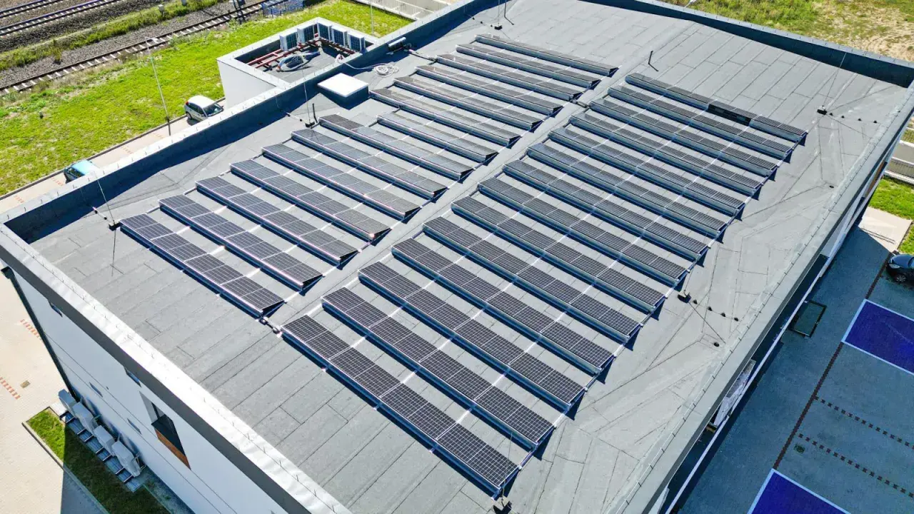 Duży płaski dach pokryty panelami fotowoltaicznymi, które zbierają energię słoneczną.