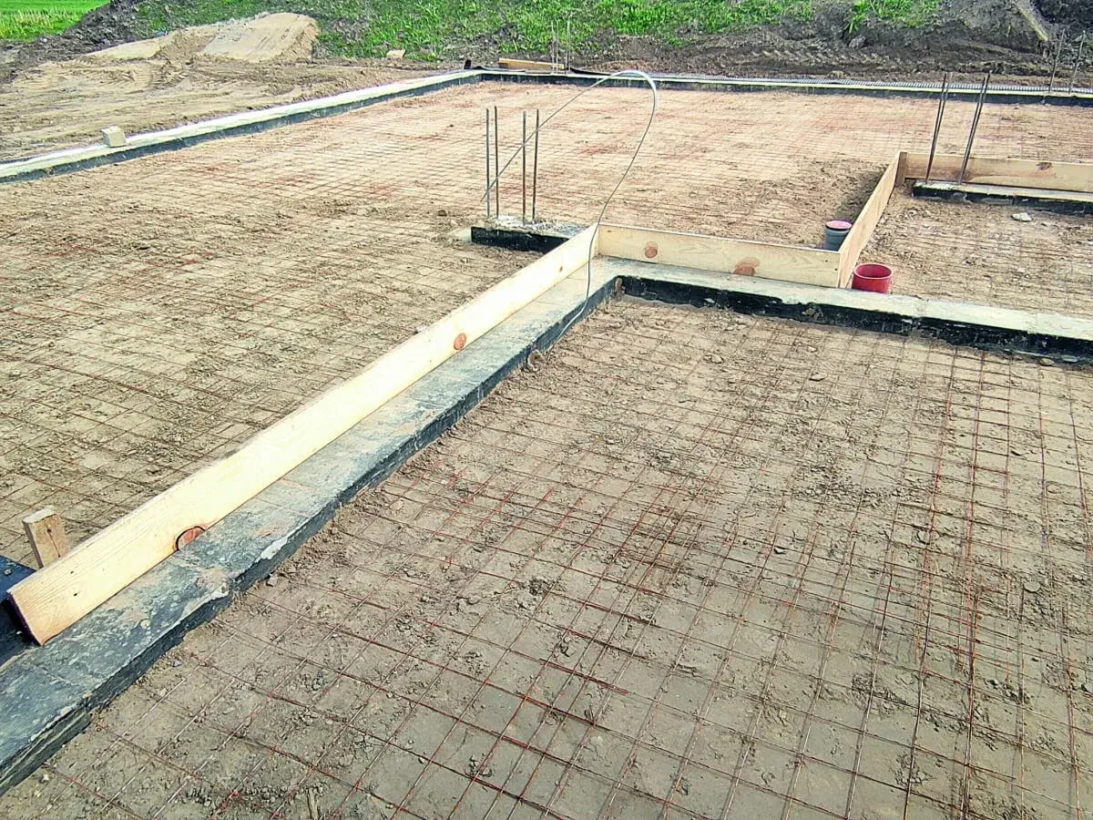 Fundament pod budowę domu, zbrojenie gotowe do zalania betonem. Widać drewniane szalunki i rury. Czekamy na chudziak.