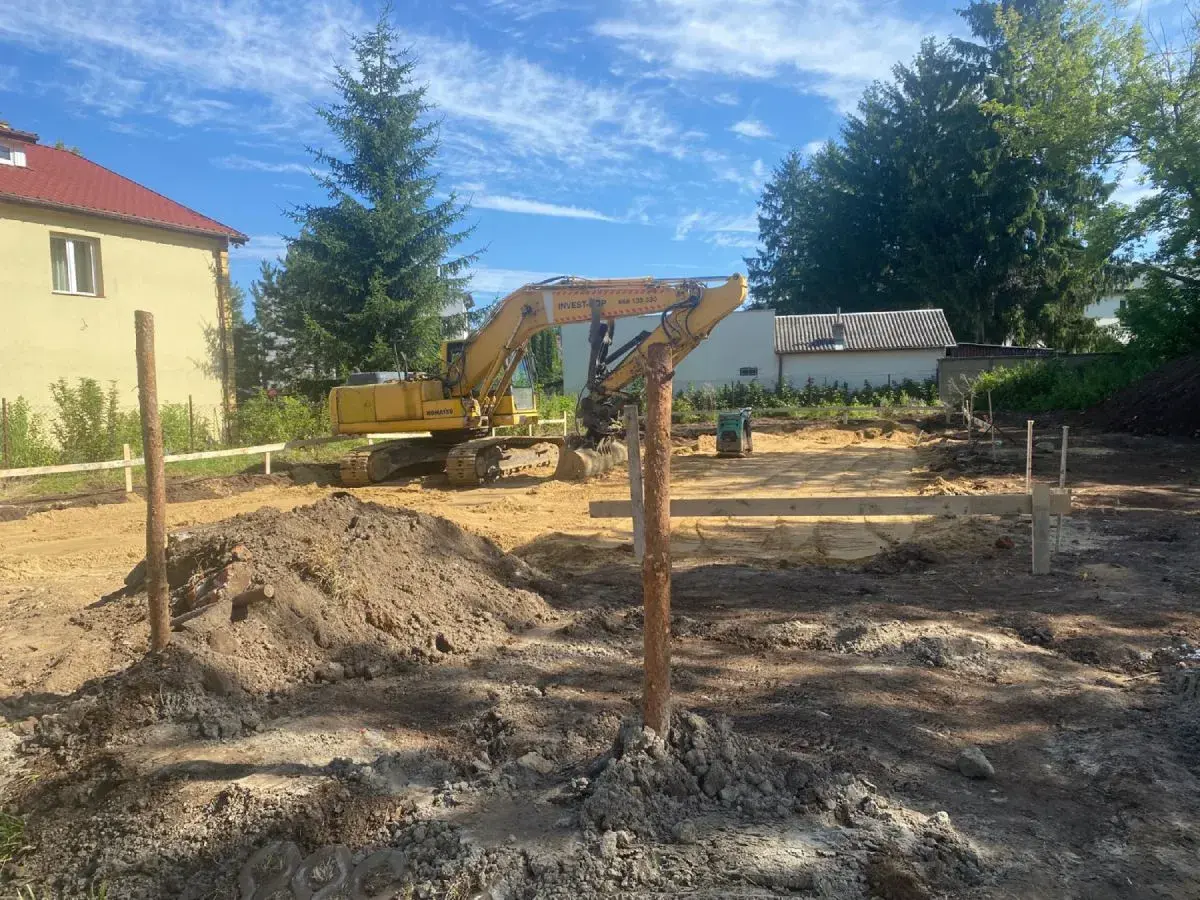 Koparka pracuje na budowie, przygotowując teren pod fundamenty. Każdy metr kwadratowy jest starannie wyrównywany.