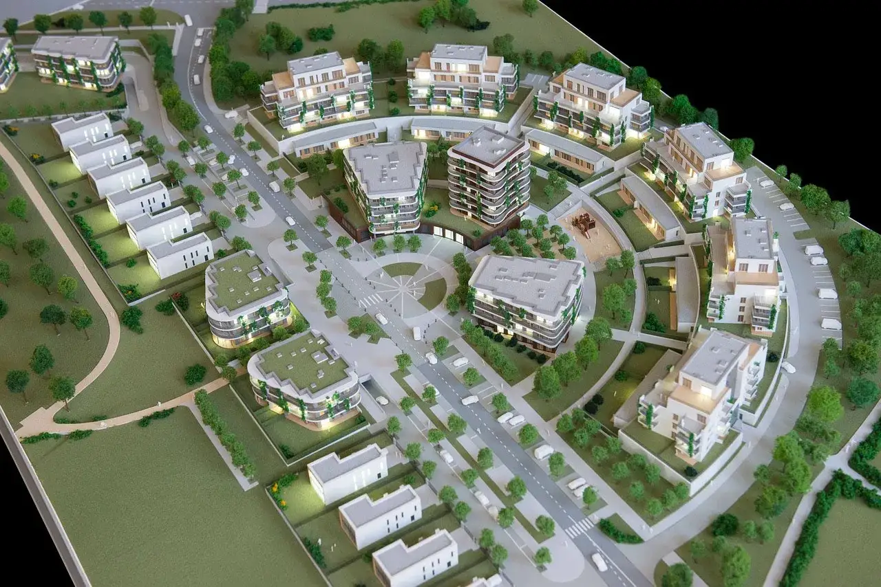 Model osiedla z budynkami mieszkalnymi i domami jednorodzinnymi. Działka budowlana zagospodarowana zielenią i infrastrukturą drogową.