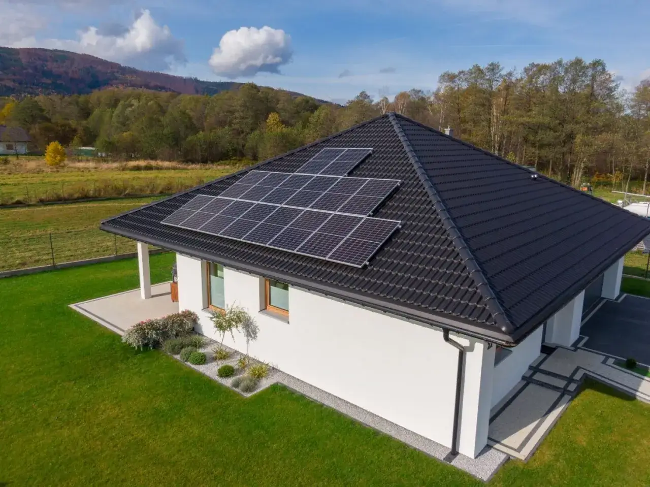 Nowoczesny dom z panelami fotowoltaicznymi na dachu. Zastanawiasz się, ile kosztuje fotowoltaika? To inwestycja w przyszłość i oszczędności.