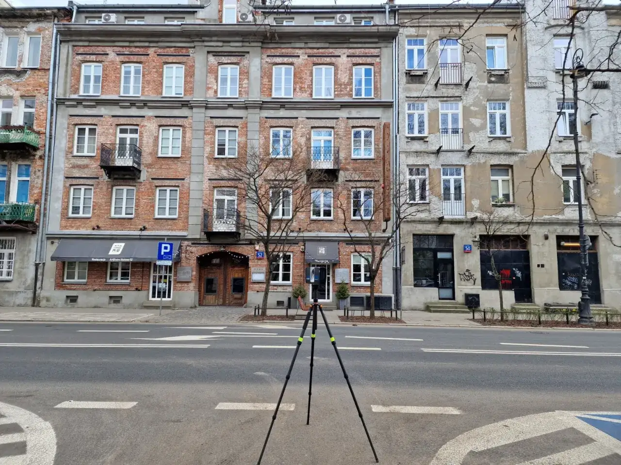 Kamienice z cegły i tynku, z balkonami i oknami. Na parterze restauracja