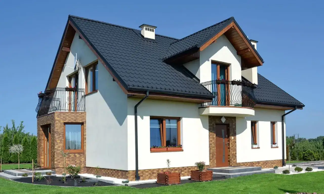 Nowoczesny dom z kamiennym wykończeniem i balkonem. Wykusz w domu dodaje mu uroku.